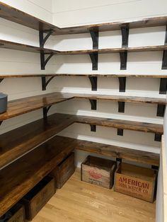 an empty pantry with wooden shelves and metal brackets on the wall, along with boxes