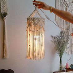 a woman is holding up a light fixture with beads and chains hanging from the ceiling