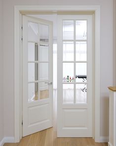 an empty room with two white doors and hard wood flooring