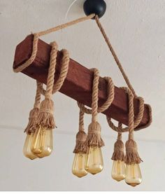 four light bulbs hanging from a wooden beam with rope and glass bulb lights attached to them