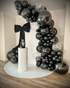 an arrangement of black and silver balloons in the corner of a room with a white column