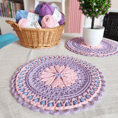 two crocheted placemats on a table next to a potted plant