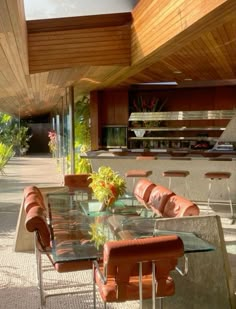 an outdoor dining area with glass table and leather chairs in front of the countertop