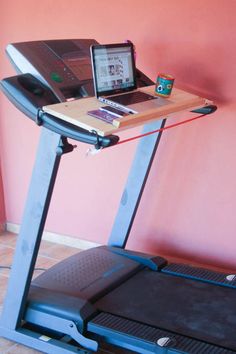 a laptop computer sitting on top of a treadmill in front of a pink wall