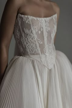 the back of a woman's wedding dress with pleated skirt and lace detailing