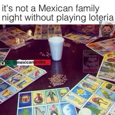 a table topped with lots of cards next to a cup filled with liquid and coins