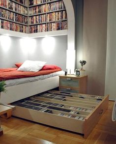 a bed sitting in the middle of a room with lots of books on the wall