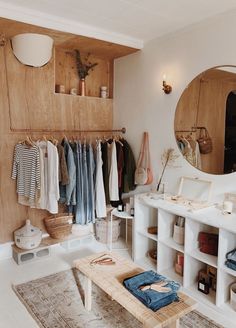 a bathroom with a sink, mirror and shelves filled with clothes