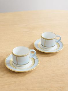 two cups and saucers sitting on top of a wooden table