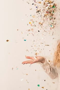 a woman is throwing confetti in the air with her hands and fingers out