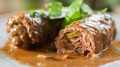 two meatballs covered in sauce and garnished with parsley on the side