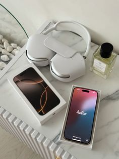 an iphone, headphones, and other electronics on a marble counter top in front of a mirror