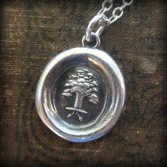 a wax seal with an image of a tree in the center on a silver chain