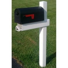 a mailbox in the middle of a grassy area next to a white post with a red letter on it