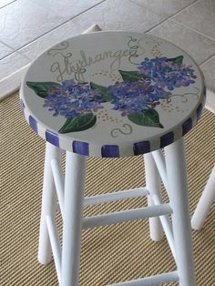 a stool with flowers painted on it sitting on the floor next to a tile floor