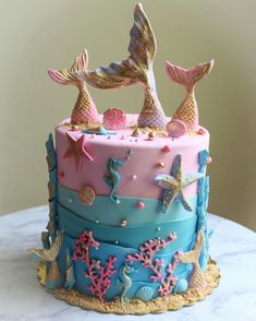 there is a cake decorated with mermaids and stars on the top, as well as other decorations