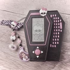 a pink and black electronic device sitting on top of a wooden table next to bracelets