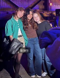 three young people posing for a photo in front of a stage with blue lights and purple lighting