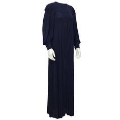 1970's navy blue, long sleeve polyester jersey gown with a yoke and hand smocking through the shoulders and bust. Cuffs have two fabric covered buttons and the sleeves are over sized with a soft drape. Invisible zipper and ten buttons up the back. Excellent vintage condition.