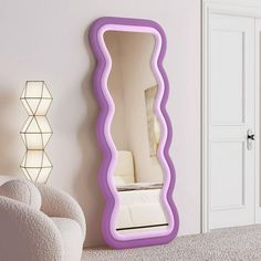 a mirror that is on the wall next to a white chair and a couch in front of it