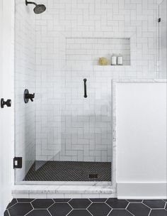 a bathroom with black and white tile flooring, shower head, and toilet in the corner