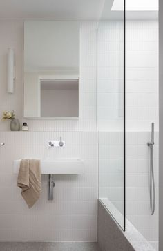 a bathroom with a sink, mirror and bathtub next to a shower head mounted on the wall