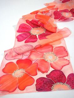 two pieces of pink and orange fabric with flowers on them are laying next to each other