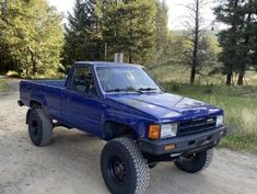 a blue pick up truck parked on top of a dirt road