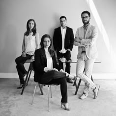 four people are sitting in chairs and posing for a black - and - white photo