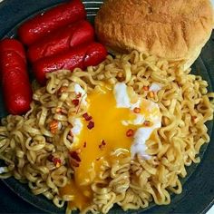 a plate with noodles, hotdogs and bun on it next to some bread