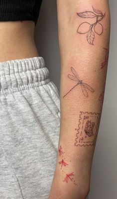 a woman's arm with tattoos on it, including an envelope and dragonfly