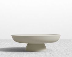 a large white bowl sitting on top of a cement floor next to an empty wall