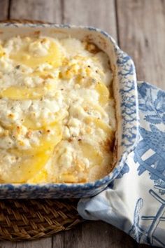 a casserole dish with cheese on top in a blue and white dishcloth