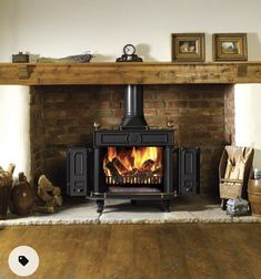 a wood burning stove sitting on top of a wooden floor next to a fire place