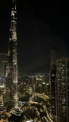 an aerial view of a city at night with skyscrapers lit up in the background