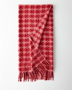 a red and white patterned scarf with fringes on the ends, against a white background