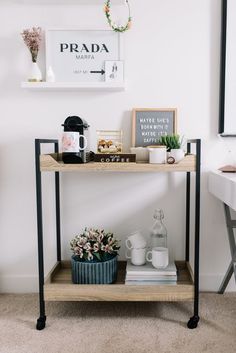 a shelf with flowers, coffee cups and other items on it next to a desk