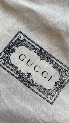 the gucci logo is on top of a white shirt with black and gold trim