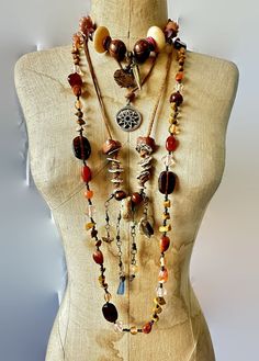 This is an instant, funky, vintage bohemian influenced collection!  Let your bohemian hippie soul sing with this layered set of 4 necklaces.  Wear them together or on their own to create different looks. The necklaces are a combination of metals, patterns, materials and finishes for an amazing assortment! Natural neutral colors of brown, black, natural wood tones and etc.   (1) Very unique handcrafted necklace.  This has a leather suede necklace.  The clasp it is a chunk of sea glass!  Now check out the the pendant section!  Rustic ceramic, snake skin spacers etc.  A chunk of rock is in the center. Dangles are created from seashell, shark's tooth, and blue sea grass!  Unique treasures!  This comes from my own collection.  It is 30" long plus 5" longest dangle.  Great condition. (2) Long be Beaded Shark, Ceramic Snake, Suede Necklace, Rustic Ceramics, Wood Tones, Shark Tooth, Handmade Wire Jewelry, Bohemian Hippie, Shark Teeth