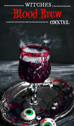 a glass filled with liquid sitting on top of a metal tray covered in fake eyes