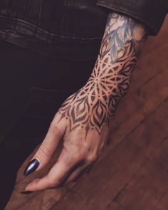 a woman's hand with an intricate tattoo design on her left arm and wrist