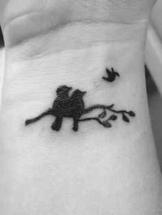 a small tattoo on the wrist of a woman with birds flying around her neck and behind her arm