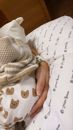 a woman is laying in bed with her hand on the pillow that she has wrapped around