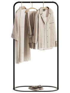 two shirts hanging on clothes racks with shoes underneath them and an open jacket hanger in the background