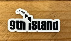 the 9th island sticker is on top of a wooden table with a piece of wood next to it