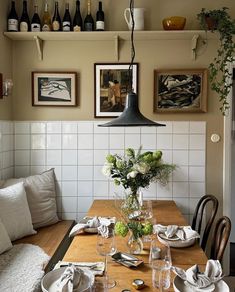 a dining room table with place settings and wine bottles on the wall