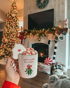 someone holding up a coffee cup in front of a christmas tree with presents on it