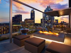 an outdoor fire pit on the roof of a building with city lights in the background