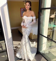 a woman in a white wedding dress is standing by a window and looking at the camera