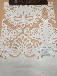 the white lace is sitting on top of a brown table cloth with a label that says prowng textiles